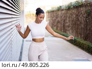 A stylish and vibrant young woman joyfully dances with expressiveness and enthusiasm in a contemporary urban environment, showcasing her carefree spirit and lively energy, radiating happiness and fun. A Joyful, Young Woman Dancing Gracefully in a Vibrant Urban Setting Full of Life. Стоковое фото, агентство Ingram Publishing / Фотобанк Лори