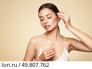 Young beautiful woman applying face serum with pipette. Cosmetic procedures for facial skin care. Стоковое фото, агентство Ingram Publishing / Фотобанк Лори