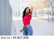 A stylish, confident young woman displays her unique fashion outdoors in a vibrant red top and trendy blue jeans, radiating positivity and inspiring others with her fun and free lifestyle. A Confident Young Woman Posing Outdoors with a Great Sense of Style and Attitude. Стоковое фото, агентство Ingram Publishing / Фотобанк Лори