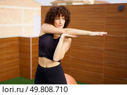 In a lively outdoor space, a curlyhaired woman showcases her fitness and flexibility with dynamic stretching, highlighted by a modern backdrop that amplifies her energy and determination. Dynamic Fitness Pose A Woman with Curly Hair Gracefully Stretching in the Great Outdoors. Стоковое фото, агентство Ingram Publishing / Фотобанк Лори