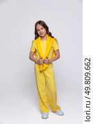 Cheerful funny genius positive little girl with curly hair in summer yellow suit has fun, jumping, dancing on white background. Happy childhood concept. Copy space. High quality photo. Стоковое фото, фотограф Ирина Михайличенко / Фотобанк Лори