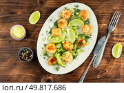 A plated dish of sea scallops garnished with fresh lime and basil sauce on wooden rustic background.. Fried scallops with sauce. Стоковое фото, агентство Ingram Publishing / Фотобанк Лори