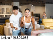 Portrait of couple choosing new sofa in furniture salon shopping room. Стоковое фото, фотограф Яков Филимонов / Фотобанк Лори