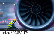 A man is kneeling down next to a large jet engine. Стоковое AI-изображение, AI-художник Ярославский Максим / Фотобанк Лори