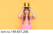 Young woman in pink dress placing gold crown on head, arrogant expression, satire concept, funny attitude, royal theme, humor scene, modern queen, playful mood, sarcastic fashion, confident pose. Стоковое AI-изображение, AI-художник Павел Муравьев / Фотобанк Лори