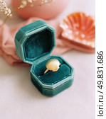 Elegant gold seashell ring displayed in a teal velvet box, surrounded by soft pink accents, symbolizing luxury, romance, and delicate coastal-inspired jewelry design. Стоковое AI-изображение, AI-художник Катерина Бондарец / Фотобанк Лори