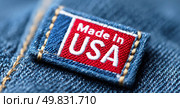 Close-up of a "Made in USA" fabric label stitched on denim, symbolizing American manufacturing, textile quality, and national branding in the fashion industry. Стоковое AI-изображение, AI-художник Катерина Бондарец / Фотобанк Лори