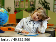 Young First-Grader Engaged in Reading Activity With Curiosity in a Colorful Classroom Setting. Стоковое фото, фотограф Aleksandr Golubev / Фотобанк Лори