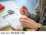 Close-up of craftswoman hands creating wool felt figure using needle felting technique, showcasing the process of transforming wool fibers into art. Стоковое фото, фотограф Ольга Ильина / Фотобанк Лори