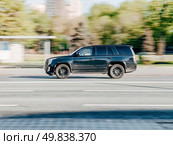 Fast moving Cadillac Escalade ESV on the city road. Black SUV with man driving. Premium auto in fast motion with blurred background. Speeding in the city concept. Редакционное фото, фотограф Константин Григорьев / Фотобанк Лори
