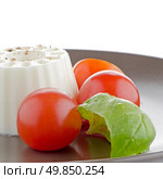 Fresh salad with goat cheese, tomato and basil pesto on a brown plate. Стоковое фото, агентство Ingram Publishing / Фотобанк Лори