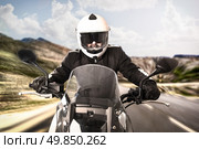 Biker in helmet and black jacket riding on the road. Стоковое фото, агентство Ingram Publishing / Фотобанк Лори