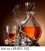 Decanter abd glass of alcohol and cigar on ashtray. Стоковое фото, агентство Ingram Publishing / Фотобанк Лори
