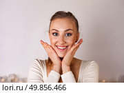 Young Woman Expresses Joy and Excitement in a Bright Studio Setting With a Neutral Backdrop. Стоковое фото, фотограф Aleksandr Golubev / Фотобанк Лори