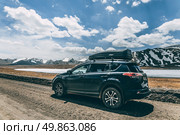 Black car on the side of a gravel road in a natural location. Toyota RAV-4 with roof rack. Road trip. Arabel plateau, Barskoon gorge. Редакционное фото, фотограф Екатерина Якименко / Фотобанк Лори
