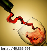Pouring red wine in goblet on yellow background. Стоковое фото, агентство Ingram Publishing / Фотобанк Лори