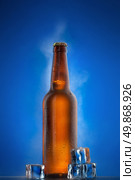 Cold beer bottle with drops, frost and vapour on blue. Стоковое фото, агентство Ingram Publishing / Фотобанк Лори