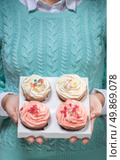 young woman holding a box of colorful cupcakes decorated with hearts and stars. Стоковое фото, агентство Ingram Publishing / Фотобанк Лори