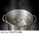 Boiling water in a kitchen pot as a symbol of cooking or food preparation and sterilization of contaminated tap water for healthy pure drinking liquid on a black background. Стоковое фото, агентство Ingram Publishing / Фотобанк Лори