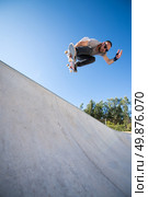 Skateboarder flying over a ramp on blue clear sky. Стоковое фото, агентство Ingram Publishing / Фотобанк Лори