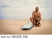 Surfer tying his surfboard’s leach on the beach. Стоковое фото, агентство Ingram Publishing / Фотобанк Лори