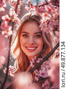 A beautiful woman with long blonde hair and piercing blue eyes stands gracefully amidst the delicate pink cherry blossoms of a tree. Стоковое AI-изображение, AI-художник Данила Большаков / Фотобанк Лори