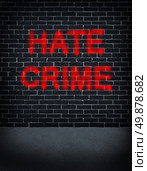 Hate crime social problem concept with a dark grey brick wall with graffiti spray can paint painted on the building structure as a symbol of racism and race discrimination as an illegal racial act of hatred and vandalism based on fear and xenophobia. Стоковое фото, агентство Ingram Publishing / Фотобанк Лори