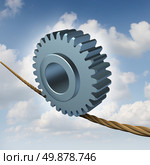 Business balance concept with a gear or cog wheel on a high wire tightrope as a guidance metaphor for investment risk with the hazards and pit falls of industry challenges on a summer sky background. Стоковое фото, агентство Ingram Publishing / Фотобанк Лори