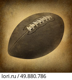 Old grunge football as a vintage antique sports symbol on a dirty parchment background as an American cultural and traditional national game and sport with leather and stitching. Стоковое фото, агентство Ingram Publishing / Фотобанк Лори