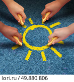 Community education and children learning and development concept with a group of hands representing ethnic groups of young people holding chalk cooperating together to draw a yellow sun shape as a metaphore for friendship. Стоковое фото, агентство Ingram Publishing / Фотобанк Лори