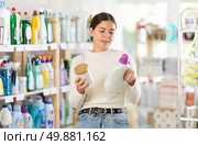 Girl reads label, choose and compare liquid detergent and powdered detergent. Стоковое фото, фотограф Яков Филимонов / Фотобанк Лори