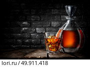 Whiskey on a wooden table in cellar with black brick wall. Стоковое фото, агентство Ingram Publishing / Фотобанк Лори