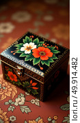 Ornate black lacquered box with vibrant floral designs and gold detailing on richly patterned fabric background. Стоковое AI-изображение, AI-художник Андрей Бакусов / Фотобанк Лори