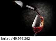 Wine pouring in wineglass on a black background. Стоковое фото, агентство Ingram Publishing / Фотобанк Лори