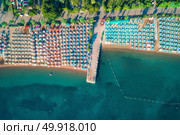 Aerial view of transparent turquoise sea, beautiful sandy beach with colorful chaise-lounges, boats, green trees at sunset in Icmeler,Turkey. Summer seascape. Top view from flying drone. Azure water. Стоковое фото, агентство Ingram Publishing / Фотобанк Лори