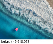 Aerial view of young woman swimming on the pink swim ring in the transparent turquoise sea in Oludeniz,Turkey. Summer seascape with girl, beautiful waves, blue water in sunny day. Top view from drone. Стоковое фото, агентство Ingram Publishing / Фотобанк Лори