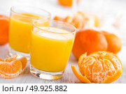 Tangerines, peeled tangerines and tangerine juice in glass. Mandarine juice. Стоковое фото, агентство Ingram Publishing / Фотобанк Лори
