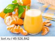 Tangerines, peeled tangerines and tangerine juice in glass. Mandarine juice and fresh fruits with leaves. Стоковое фото, агентство Ingram Publishing / Фотобанк Лори