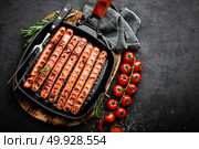 Grilled sausages bratwurst in grill frying-pan on black background. Top view. Traditional German cuisine. Stock image. Стоковое фото, агентство Ingram Publishing / Фотобанк Лори