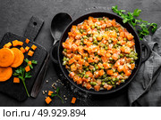 Carrot braised with fresh green peas in creamy milk sauce in stewpan, vegetable saute on black background, top view. Стоковое фото, агентство Ingram Publishing / Фотобанк Лори