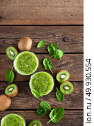 Kiwi smoothie drink of spinach leaves and fresh fruits on wooden rustic table, healthy detox diet . Стоковое фото, агентство Ingram Publishing / Фотобанк Лори