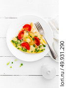Omelet. Eggs fried. Scrambled eggs with green onion and fresh tomato. Omlette on white plate. Breakfast. Top view. White wooden background. Стоковое фото, агентство Ingram Publishing / Фотобанк Лори