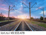 Railroad and beautiful sky at sunset. Industrial landscape with railway station, colorful blue sky with clouds, trees and green grass, yellow sunlight in summer. Railway junction. Heavy industry. Railroad and beautiful sky at sunset. Railway. Стоковое фото, агентство Ingram Publishing / Фотобанк Лори