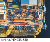Aerial view of ships and boats in dry dock for repairs. Top view of iron rusting ship is in dry dock for refurbishing. Industrial scene with old yachts, buildings, tree and football field at sunset. Aerial view of ships and boats in dry dock. Aerial view of ships and boats in dry dock. Стоковое фото, агентство Ingram Publishing / Фотобанк Лори