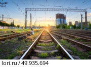 Railroad at beautiful sunset in Europe. Industrial landscape with railway station, green grass, buildings, blue sky with sun. Railway junction in the evening. Railway platfform. Transportation.  . Industrial landscape with railway station, green grass, buildings. Стоковое фото, агентство Ingram Publishing / Фотобанк Лори