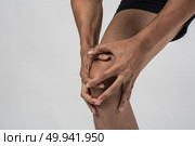 Young sport man with strong athletic legs holding knee with his hands in pain after suffering ligament injury  isolated on white.. Young sport man with strong athletic legs holding knee with his . Стоковое фото, агентство Ingram Publishing / Фотобанк Лори