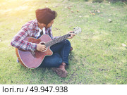 Young hipster man practiced guitar in the park,happy and enjoy p. Young hipster man practiced guitar in the park,happy and enjoy playing guitar. Стоковое фото, агентство Ingram Publishing / Фотобанк Лори