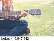 Young hipster man practiced guitar in the park,happy and enjoy p. Young hipster man practiced guitar in the park,happy and enjoy playing guitar. Стоковое фото, агентство Ingram Publishing / Фотобанк Лори