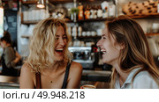 Two women sitting at a bar, engaged in laughter and conversation. Стоковое AI-изображение, AI-художник Данила Большаков / Фотобанк Лори