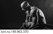 A man with tattoos on his back sitting in a wheelchair. Стоковое AI-изображение, AI-художник Данила Большаков / Фотобанк Лори